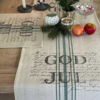 Beige juledækkeservietter lagt på bordet med løber i samme design