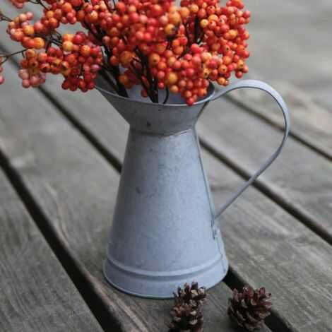 zink kande med hank her med grene stående til pynt udenfor