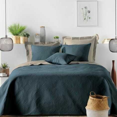 Flere blå pudebetræk lagt på innerpuder som pyntepuder oven på sengetæppe i soveværelse