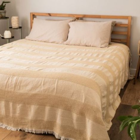 Gult sengetæppe med frynser lagt på dobbeltseng