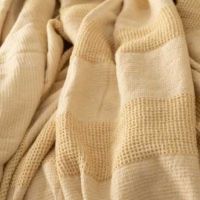 Gult sengetæppe set tæt på mønsteret i materialet