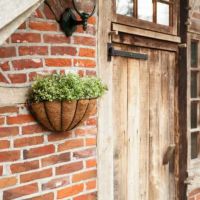 Blomsterkurv til væg ophægt på muren ved hoveddøren med planter