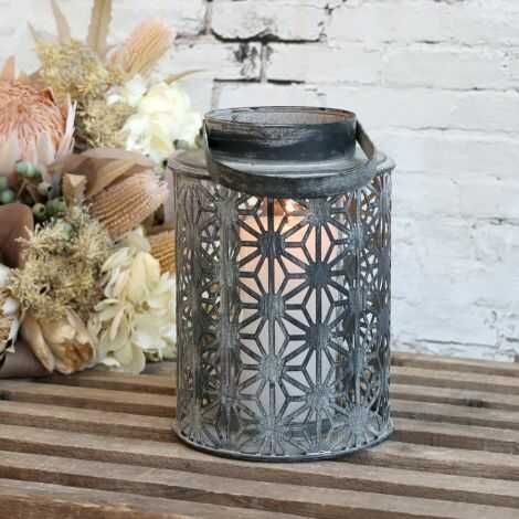 Udendørs lanterne stor med bloklys tændt på havebordet