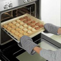 ovn handsker på dame der tager en bageplade ud af ovnen