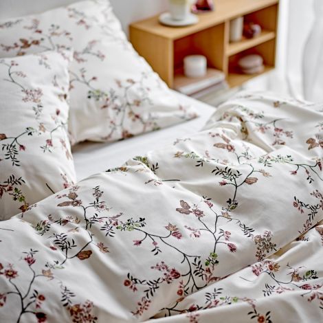 Lækkert sengetøj med blomster mønster i rosa farver redt op på seng i soveværelset