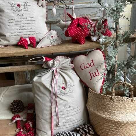 Gavesæk med print fyldt med pakker stillet hyggeligt op ved et juletræ