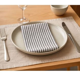 Mundserviet i stof pænt lagt på tallerken på spisebordet