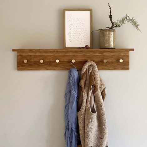 knagerække med hylde i egetræ med 7 messing knager ophængt på væg i entre